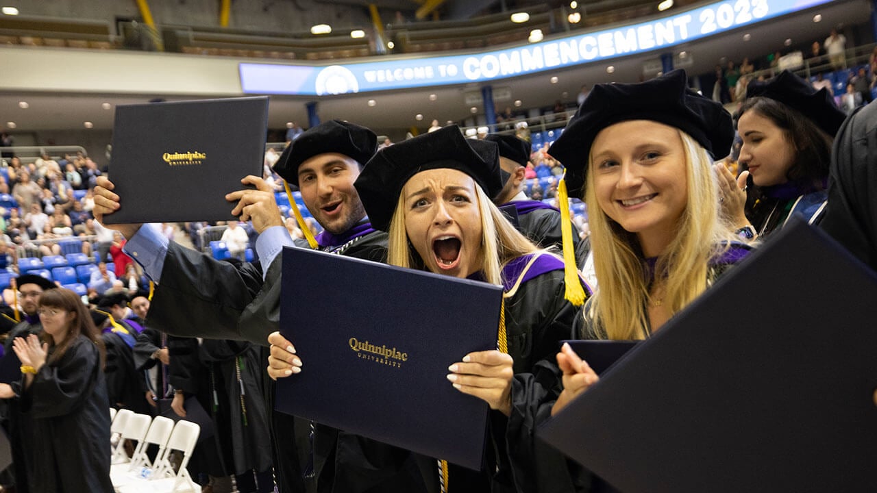 Law graduates holding up their diploma and smiling