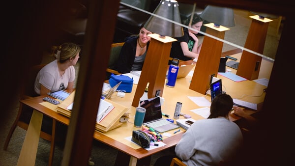 a group of 5 female students studying at the open tables in the law library