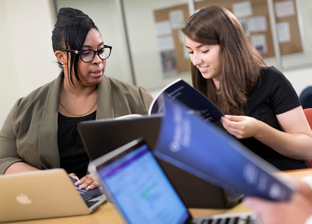 Two part-time law students smile and sit side-by-side as they work on an issue of the Probate Law Journal