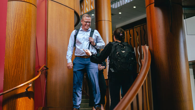 A law student smiles on the stairs of the Law Library