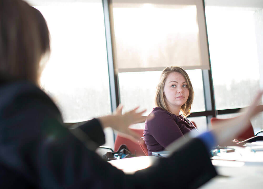 Two students sit behind their laptops and converse during a law workshop