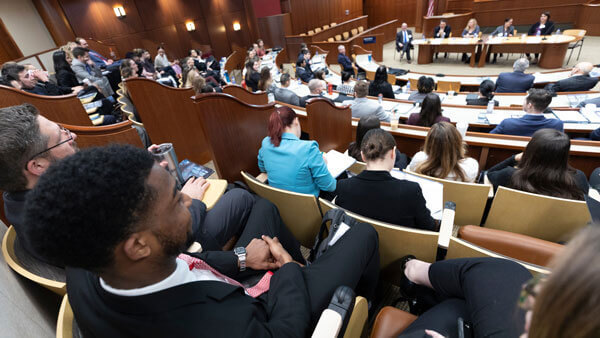 Dozens of students sit and listen to experts in the Ceremonial Courtroom