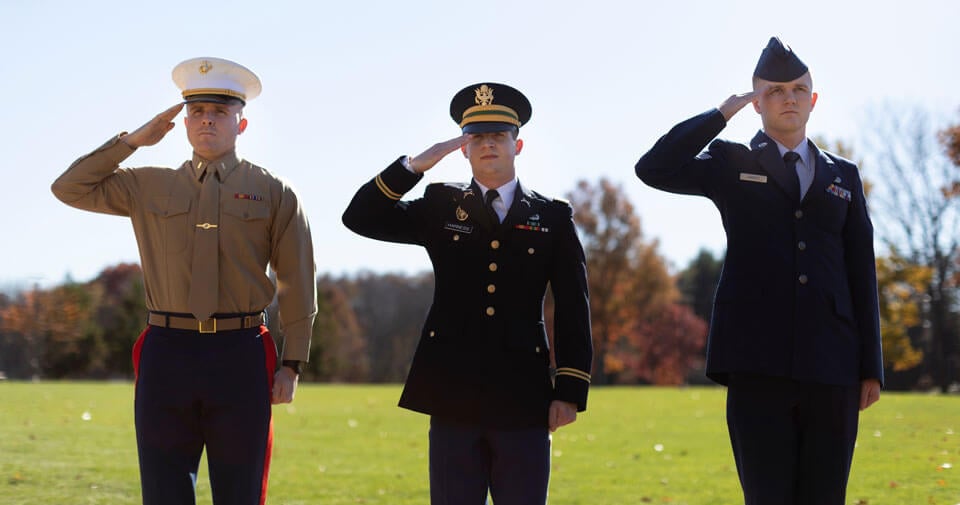 Three veteran students in the school of law salute during a ceremony